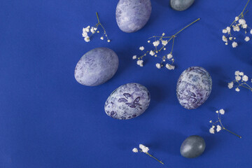 Several easter marbled purple eggs on a blue background with copy space