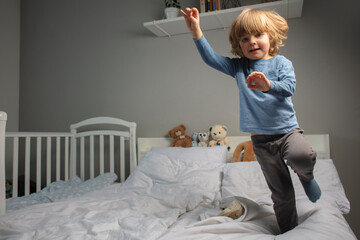 Child jumping on the parent's bed. Funny toddler. Playing baby. Baby in the motion. Happy...