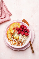 Porridge oatmeal with raspberries, peaches and nuts for breakfast. Healthy vegetarian food concept.