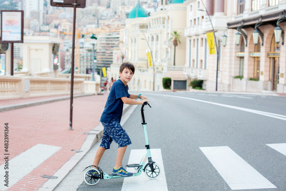 Poster Cute preteen boy, riding scooter in Monaco village on sunset