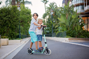 Cute preteen boy, riding scooter in Monaco village on sunset