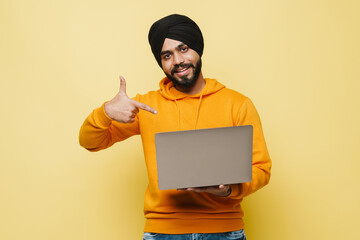 Bearded south asian man wearing turban pointing finger at his laptop