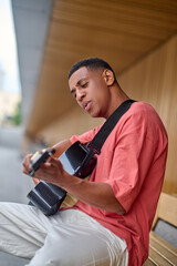 Man sitting sideways to camera playing guitar