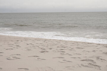 Empty Beach Footprints, Blue Sky and Ocean Gently Breaking on Sand