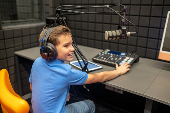 Joyous young boy sitting in the recording studio
