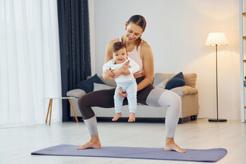 Obraz premium Teaching fitness. Mother with her little daughter is at home together