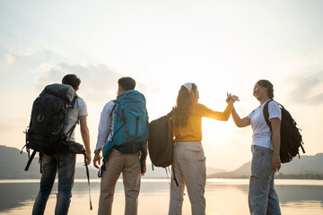 A group of Asian friends backpacking bag and walking for picnic and camping near lake