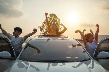 Asian friends group in car travel and Raise your hand cheerful excitement on sun roof with holiday...