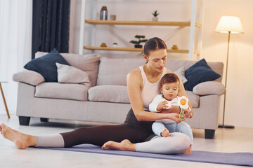 On the yoga mat. Mother with her little daughter is at home together
