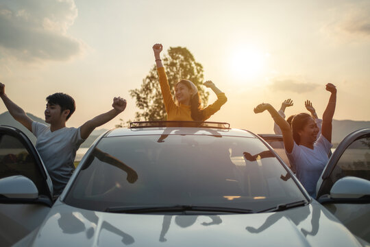 Asian friends group in car travel and Raise your hand cheerful excitement on sun roof with holiday destination. Car travel