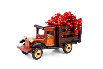 Ripe red currnat in wooden toy truck on white background.
