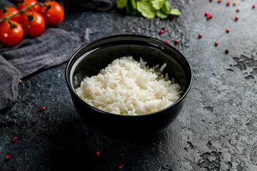 boiled rice in a black bowl on dark stone table