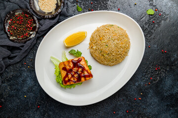 salmon steak with teriyaki sauce with rice on dark stone table