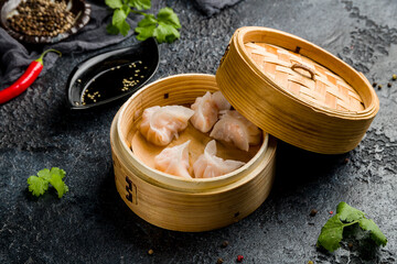 Dim sum with shrimp on wooden plate on dark stone table