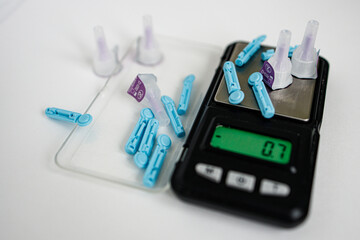 Blue lancets, needles on the scales on a white background