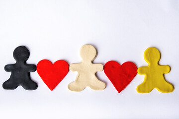 Three black, white and yellow plasticine men hold red platinum hearts in their hands on a white background. Diverse family concept. Relationship concept. Symbolism and minimalism