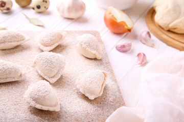 Raw dumplings with cabbage on white wooden background. Vareniki is a dish of Slavic cuisine.