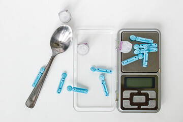 Blue lancets, needles with a spoon and scales on a white background