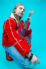 Fototapeta premium Music Ideas and Concepts. Caucasian Guitar Player Posing and Playing Electro Guitar Sitting In Fashionable Red Jacket Over Trendy Turquoise Background.