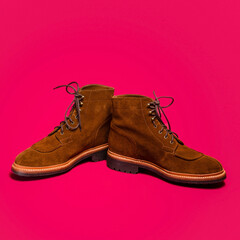 Pair of Tan Brown Suede Split Toe High Boots Closeup With Rude Rubber Sole Placed Together On Red Background.