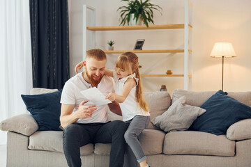 Little girl have gift for man. Father with his little daughter is at home together