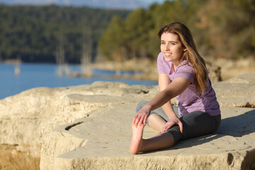 Fototapeta na wymiar Happy sportswoman stretching leg in nature