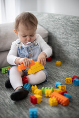 Little baby girl playing with toys at home