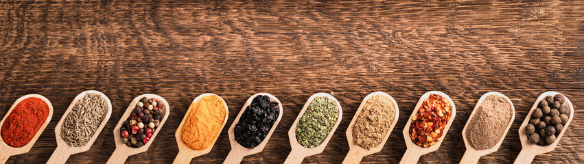 Various spices in wooden spoons top view with copy space banner