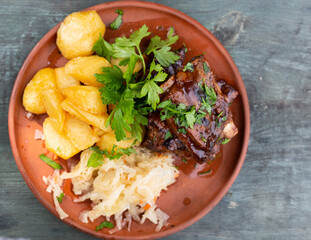 Bavarian pork ribs baked with sauce with boiled potatoes and sauerkraut