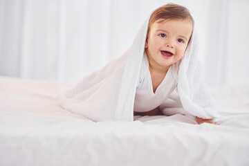 With white towel. Cute little baby is indoors in the domestic room