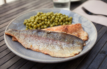 Appetizing baked trout fillets with green peas