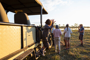 People enjoying a sundowner, drinks at sunset on a safari drive. 