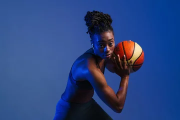 Poster Black young sportswoman in earphones working out with basketball © Drobot Dean