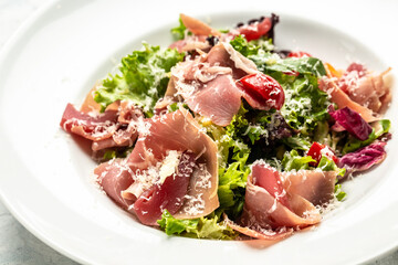 Salad with Prosciutto, ham and grapefruit jamon, salad mix, grapefruit, cherry tomatoes, parmesan cheese. Cold snacks. Food recipe background. Close up
