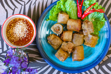 Deep fried spring rolls in blue plates with vegetables, chili and dipping sauce (Chinese food)