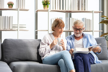 senior couple reading a book and self learning in living room