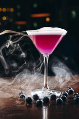 Smoking martini glass with purple drink. Cocktail with blueberries 