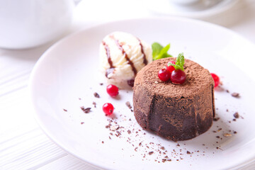 Chocolate fondant with ice cream, cranberries and mint on a white plate