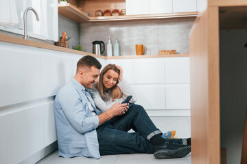 Couple sitting on the floor of modern kitchen