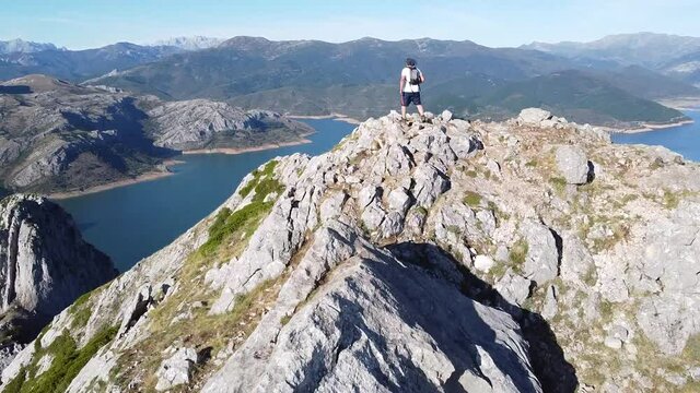 man reaching the summit of a mountain (aerial cinematic footage)