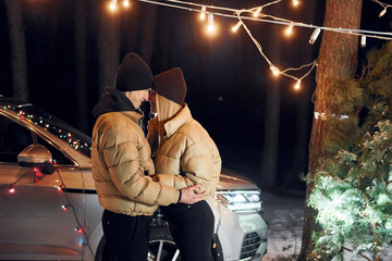 Fototapeta premium Looking at each other. Couple standing in the forest and celebrating New year