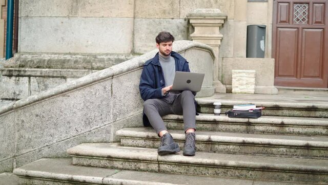 Man using laptop while sitting on stone staircase