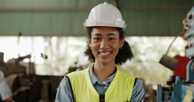 Smiling African-American Woman engineer stand in industrial factory. happiness in progressive work construction business. Enthusiasm for professional work. Worker work with confident. Blue collar