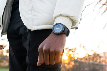 Faceless ethnic person with wristwatch in garden