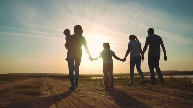 happy family. people in the park silhouette walk at sunset. mom dad and daughters walk holding hands in the park. happy family kid dream concept. parents and fun children walking back silhouette