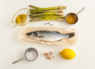 Cooking theme flat lay photo composition with raw seabass on white background.