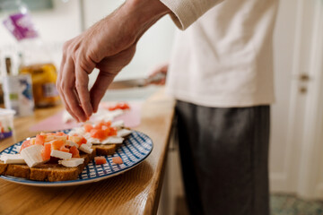 European man making sandwich with cheese in kitchen