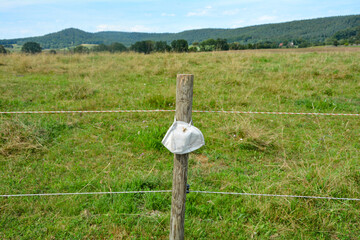 Respirator mask hanging on a wooden pole in the green nature