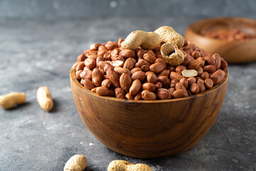Raw Peanuts in wooden bowl on natural gray rustic desk.