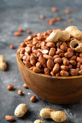 Raw Peanuts in wooden bowl on natural gray rustic desk.